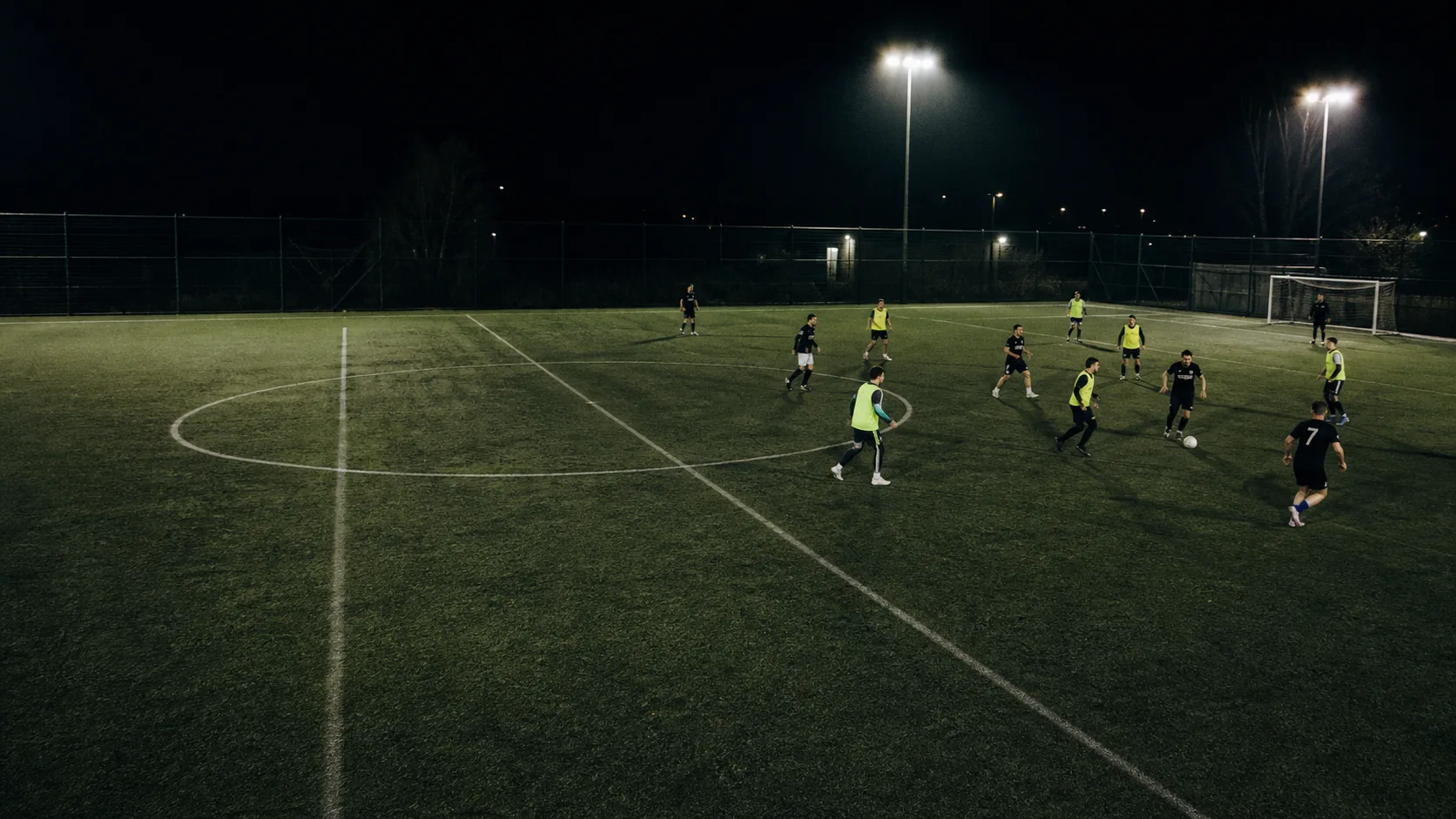 An amateur football match under floodlights